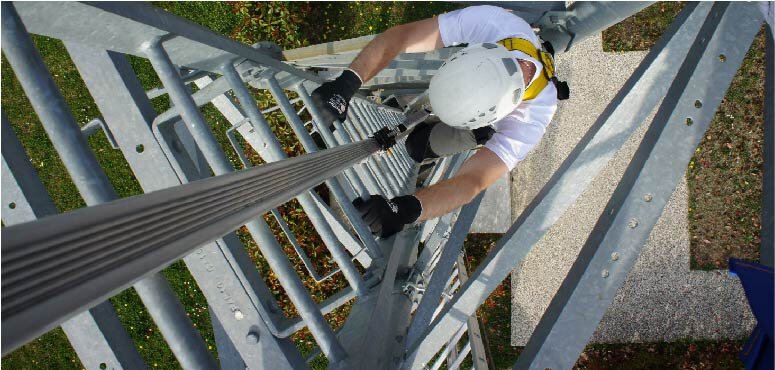 Trabajador ascendiendo por una escalera vertical de forma segura con un raíl vertical