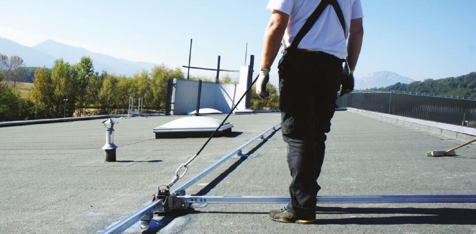 Trabajador sobre un tejado asegurado con un raíl horizontal de diferentes direcciones