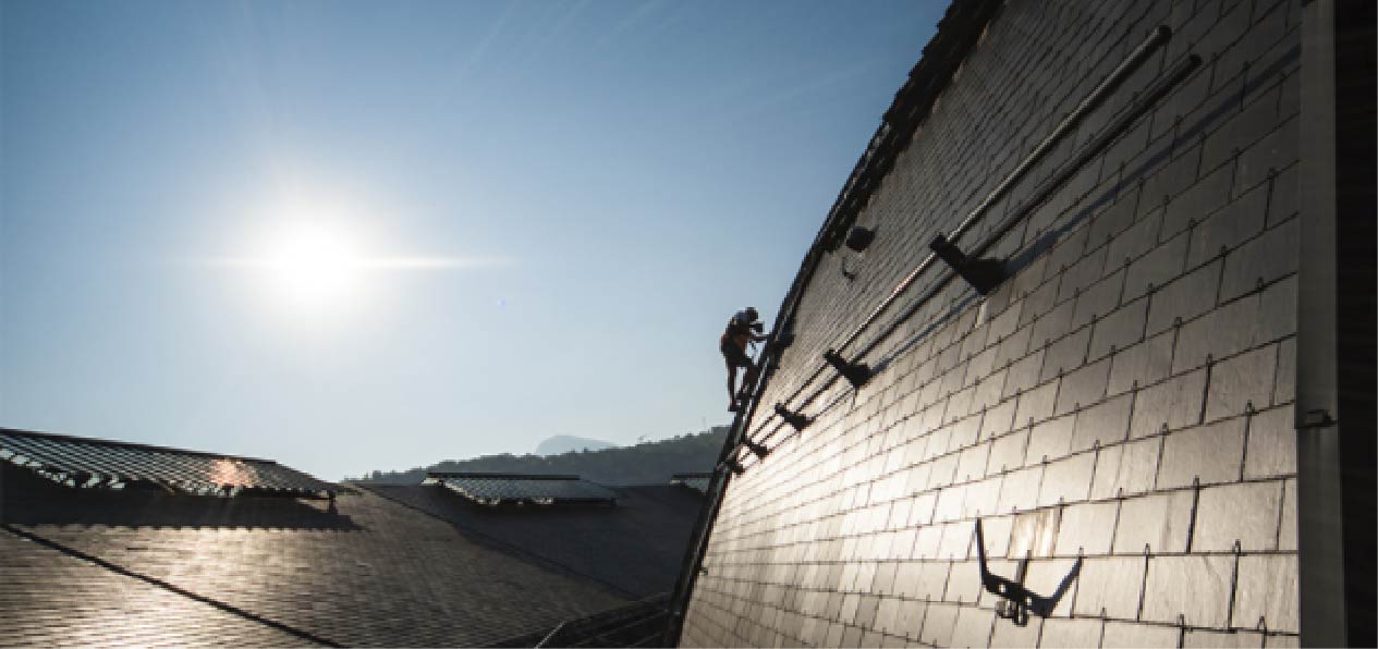 Trabajador sobre un tejado asegurado con una línea de vida inclinada u oblicua