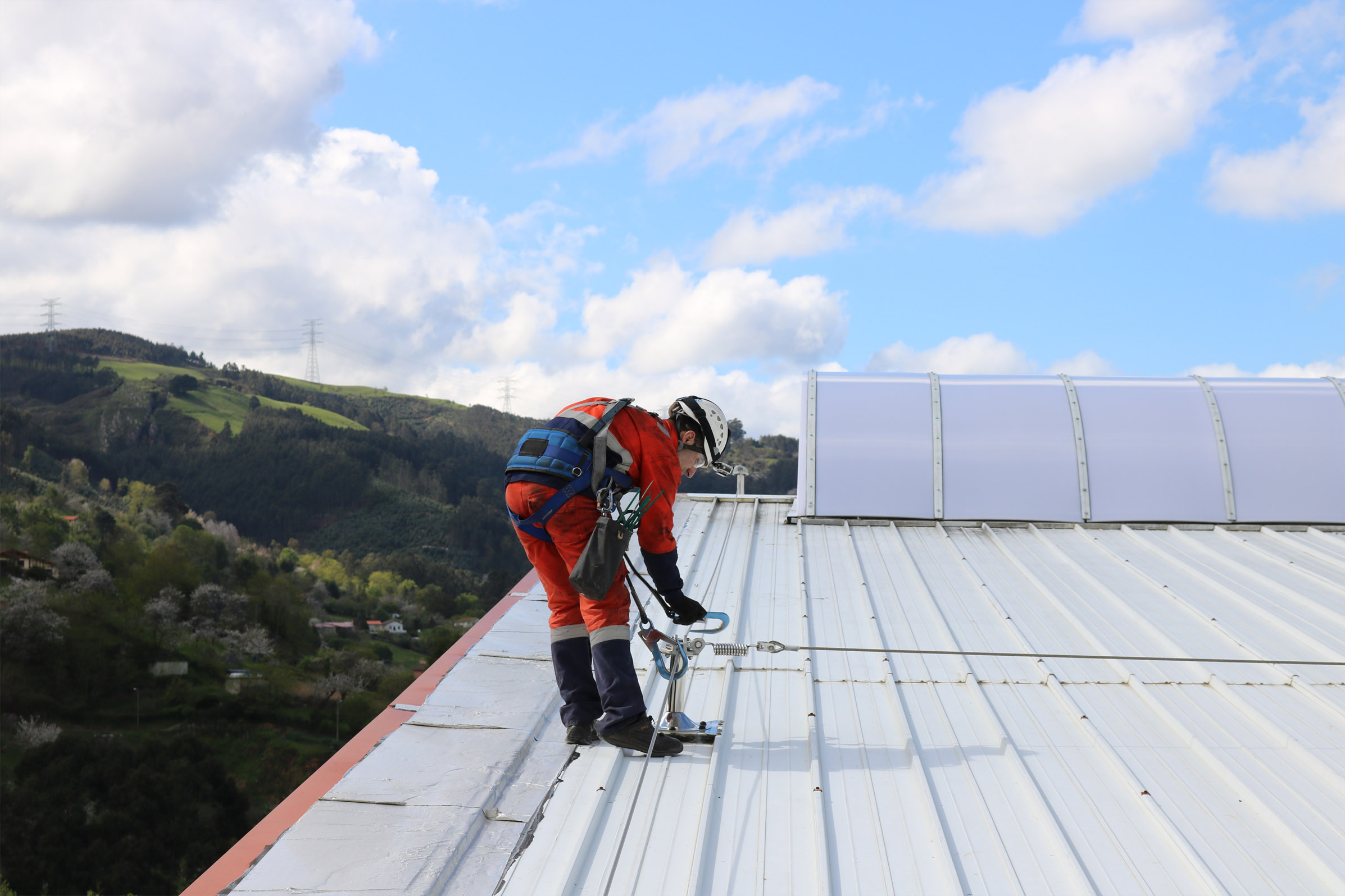 Trabajador sobre un tejado asegurado con una línea de vida horizontal